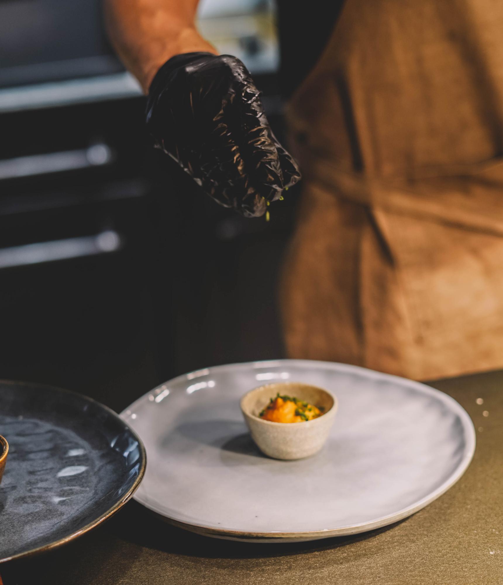Chef plating a composed dish in a calm kitchen